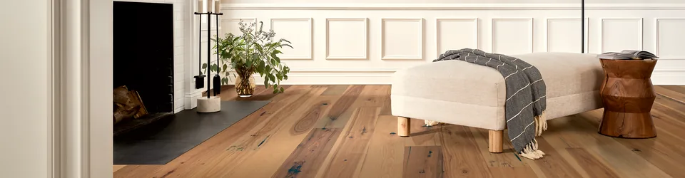 Warm wood flooring beside a cream lounge chair and fireplace